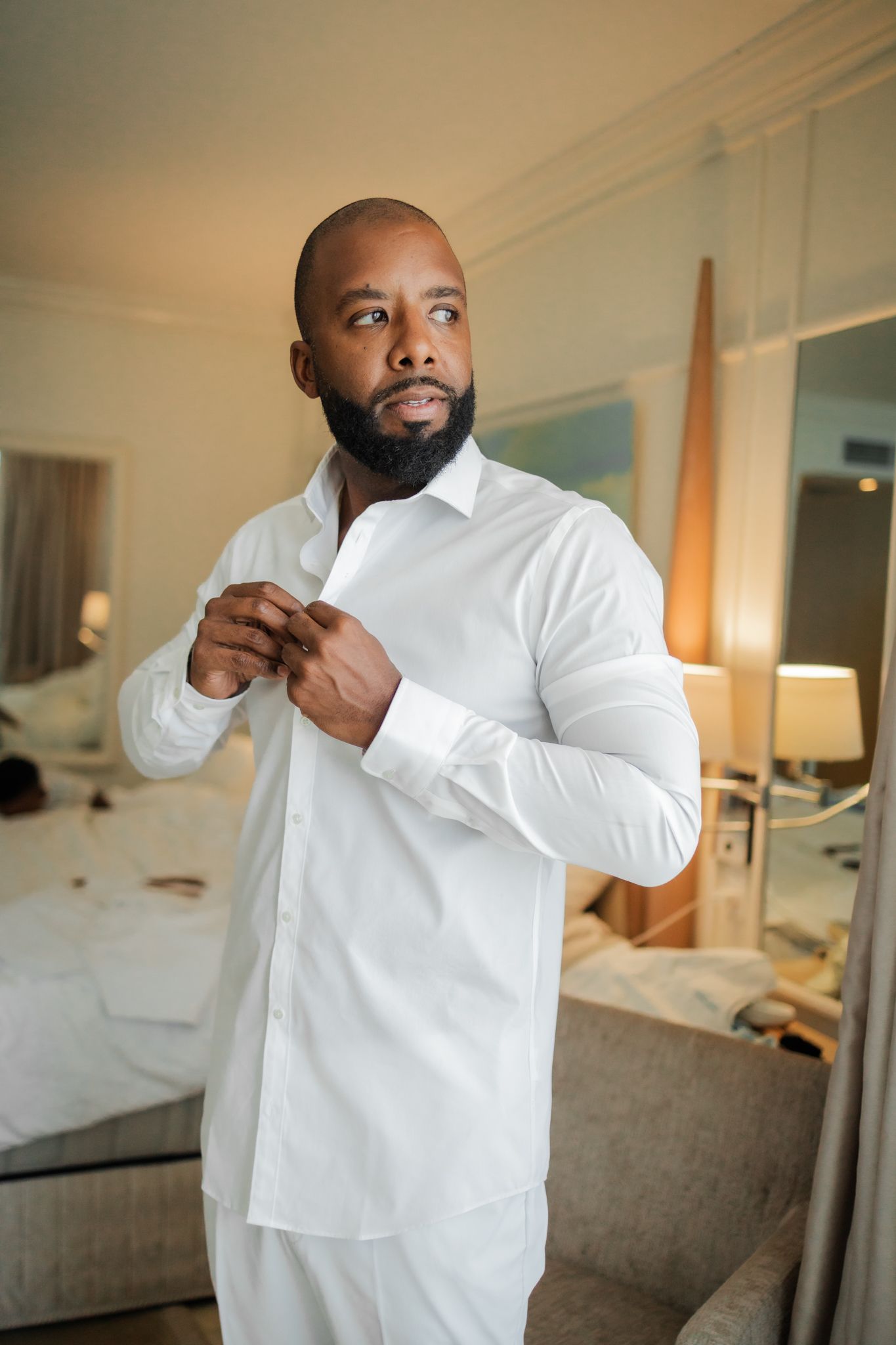 Groom buttoning white shirt getting ready for wedding at Moon Palace Jamaica